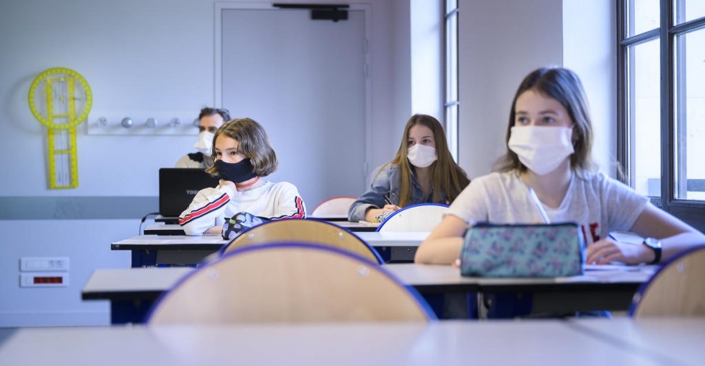 dans une classes des collégiens et des collégiennes respectent les distances physiques et portent des masques