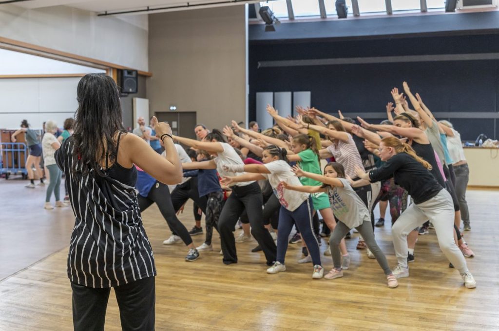 Une chorégraphe fait répéter son groupe de danseurs amateurs.